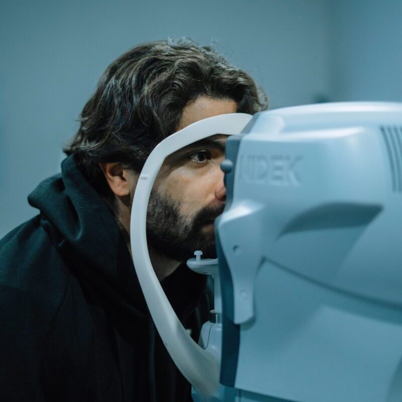 A man undergoing an eye examination using a medical device in a clinic setting.